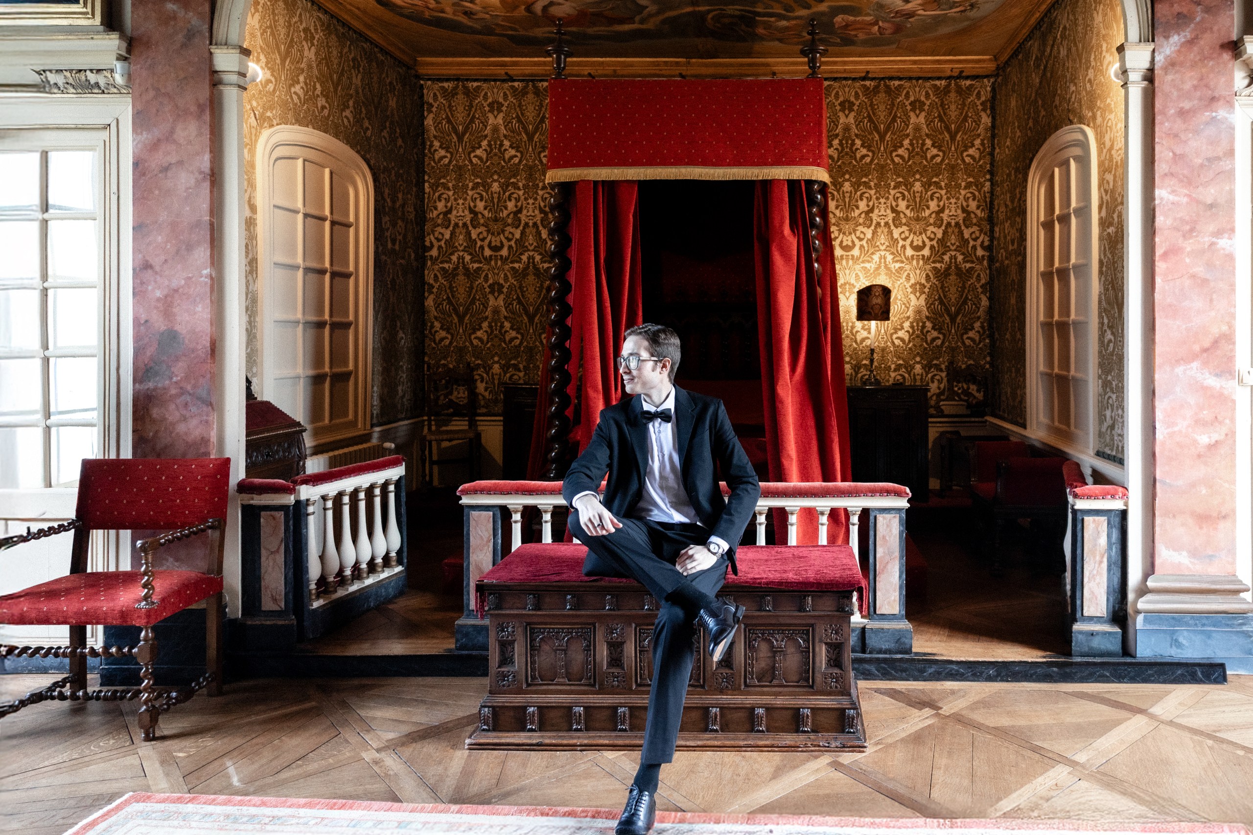 groom preparation in a beautiful chateau suite de chateau de bonnemare in red colors